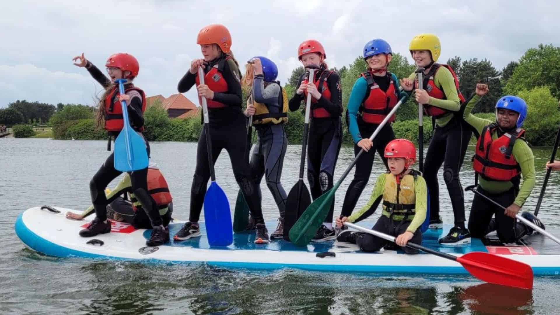Young people paddleboarding promoting group offer